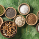 Bowls of dried grains on green background